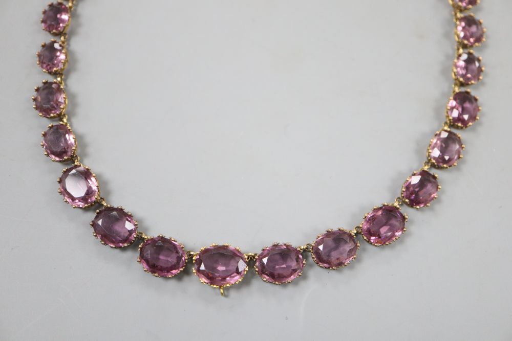 A Victorian pinchbeck and graduated amethyst coloured paste set necklace, 45.2cm, lacking central drop.